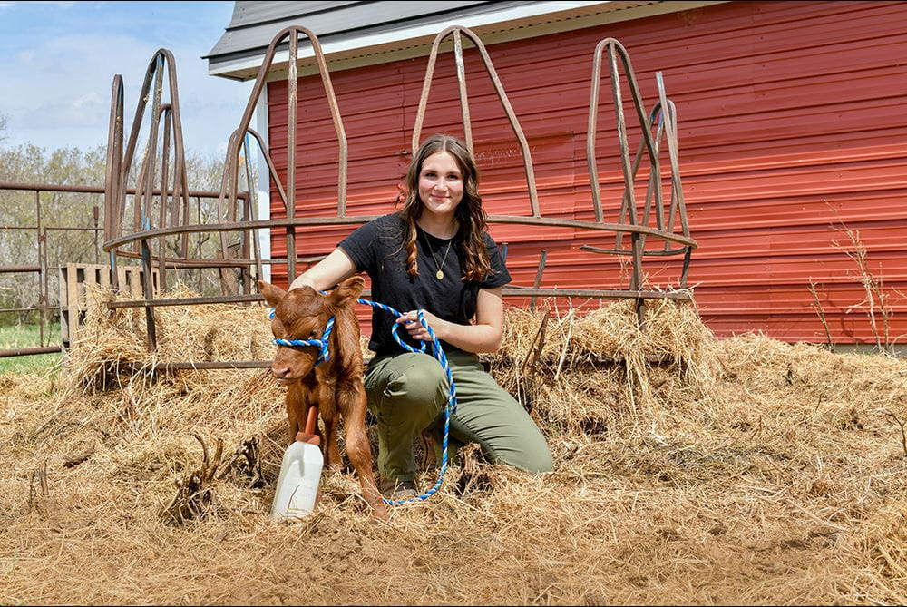 Abbey Norek beside a baby cow calf on her farm