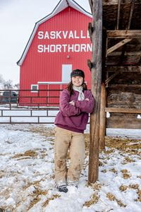 A female farmer smiles while standing in front of a red family barn