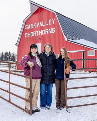 A group of women smiling in front of a red barn