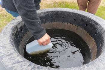 person dipping a one litre jug into a water source