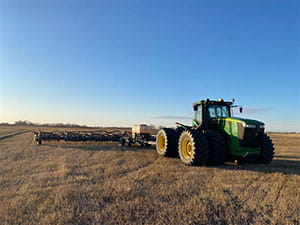 Tractor with Valmar on a harrow bar in a field