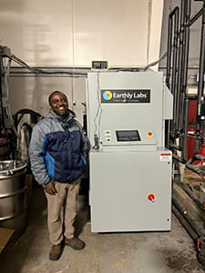 A man stands next to a carbon caption machine.