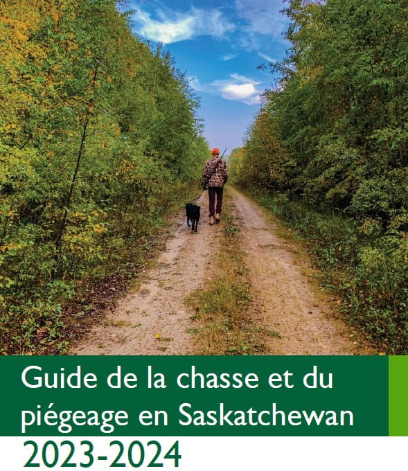 Un homme et un chien marchent sur un chemin avec des arbres. Guide de la chasse et du piégeage en Saskatchewan 2023-2024.