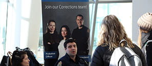 A Corrections employee speaking with students at a career fair.