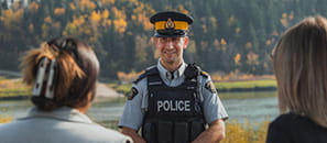 A smiling member of the Royal Canadian Mounted Police greets two citizens.