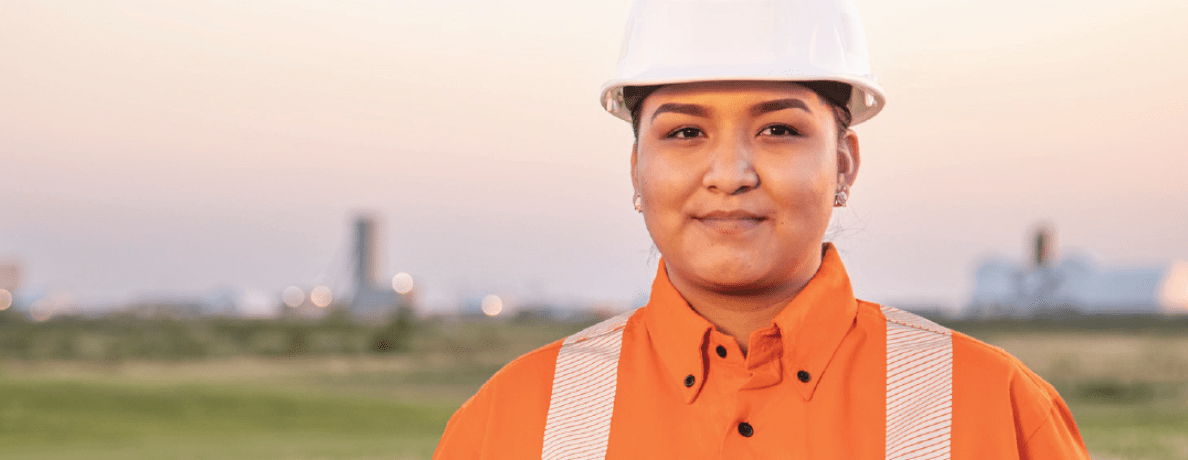 Woman in hard hat smiling at camera during dusk