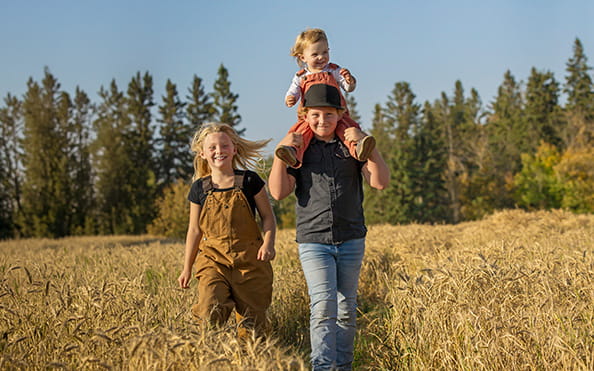 Three children walking in a wheat field