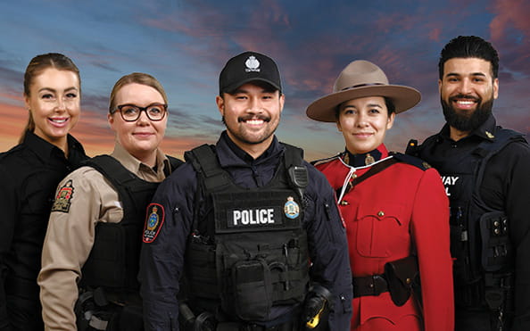 A correctional officer, conservation officer, police officer, RCMP officer and Highway patrol officer stand in front of colourful sky at dusk.