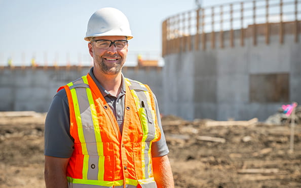 A man in a hard hat and reflective vest standing on a work site