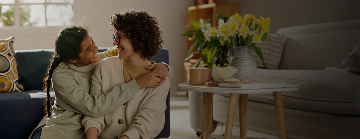 A child hugging a parent, both smiling.