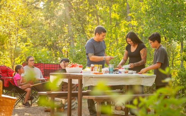 A family enjoying a picnic around a campground picnic table.