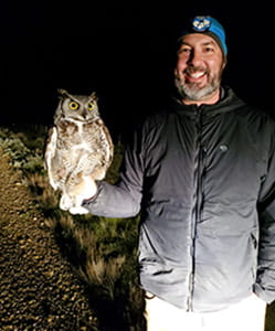 Dr. Ryan Fisher with an owl perched on his hand.