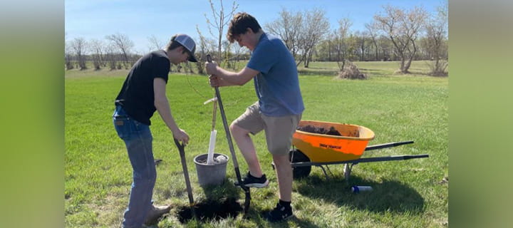 Two students digging a hole to plant a tree