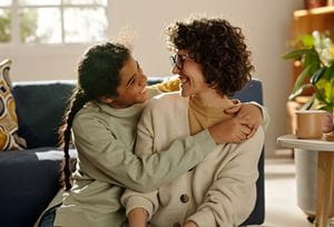 A child hugging a parent, both smiling.