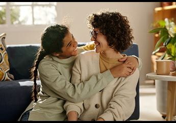 A child hugging a parent, both smiling.