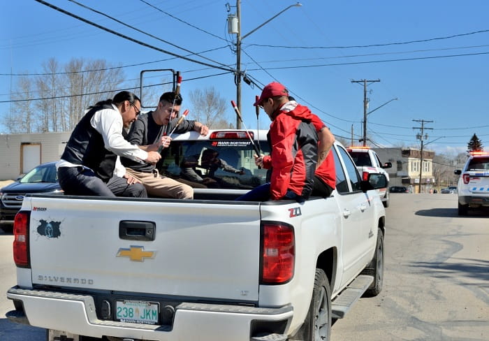 Members of the Men of the North drumming in the back of a white pickup truck during a parade in Northern Saskatchewan.