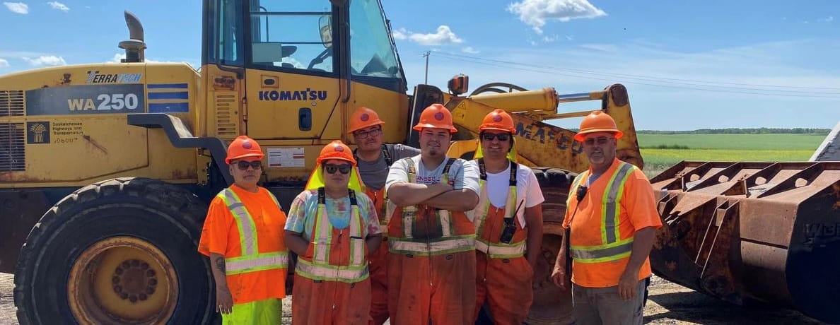 Six highway road crew workers standing in front of construction equipment