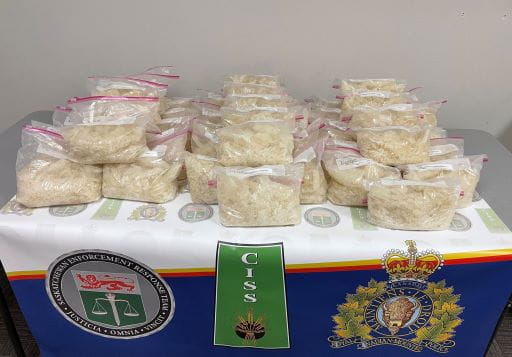 Packaged bags of seized methamphetamine, arranged on a table bearing logos of the Saskatchewan Enforcement Response Team and the RCMP.