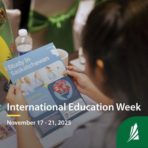 Camera overlooks a student?s shoulder while they read a brochure about studying in Saskatchewan. Text on the graphic reads ?International Education Week. November 17 ? 21, 2025.
