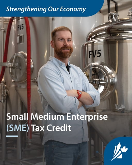 A person standing in front of a large silver tank with text that reads "Small Medium Enterprise (SME) Tax Credit"