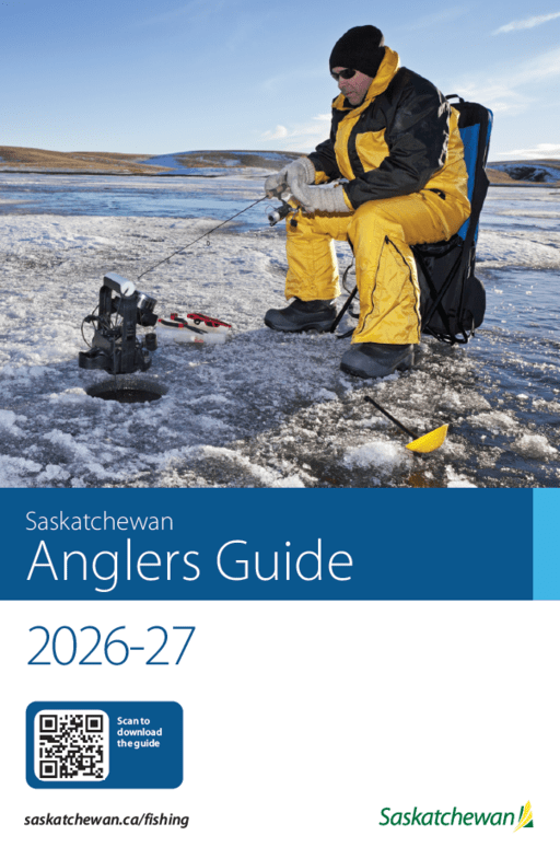 a man in a yellow winter suit, sitting down and ice fishing outside