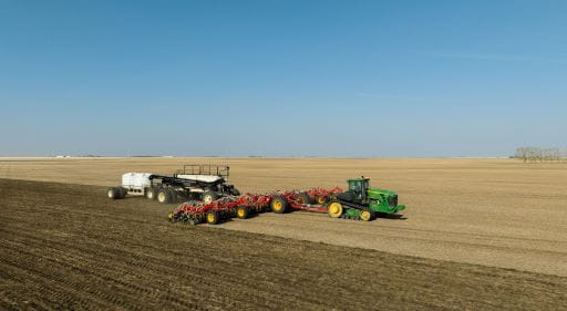 A large tractor hauling seeding equipment in a field