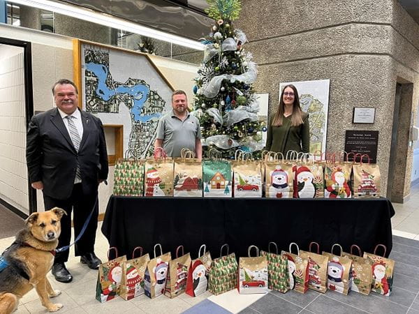 The Provincial Military Liaison and staff from the Provincial Capital Commission stand by a table filled with 50 holiday gift packages that will be sent to veterans across the province. 