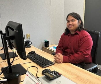 Clint, a Government of Saskatchewan summer student, poses for a photo in front of a computer.